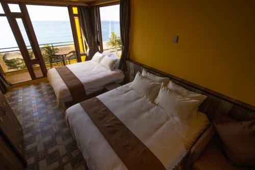 two beds in a hotel room with a view of the ocean at 花蓮諾丁漢海景民宿 Nottingham Seaview Inn in Hualien City