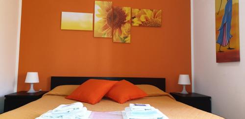 ein Schlafzimmer mit einem Bett mit orangefarbenen Wänden und 2 Lampen in der Unterkunft Domina Romae B&B in Rom