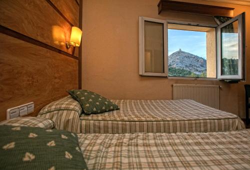 um quarto de hotel com duas camas e uma janela em Hotel Odon em Cocentaina