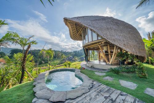 a small hut with a pool in the grass at Veluvana Bali in Sidemen