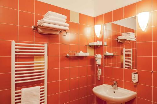 baño con paredes de azulejos de color naranja y lavabo en Equitana Hotel Resort, en Březnice