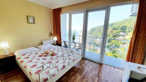 a child laying on a bed in a bedroom with a balcony at Calypso Kvariati Hotel in Kvariati