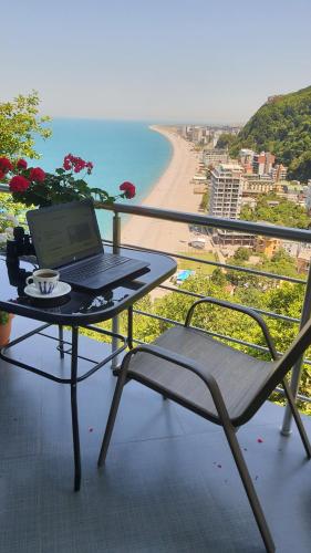 a laptop sitting on a table on a balcony with a beach at Calypso Kvariati Hotel in Kvariati