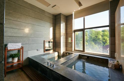 白河區的住宿－儷景溫泉會館，一间带大浴缸及大窗户的浴室
