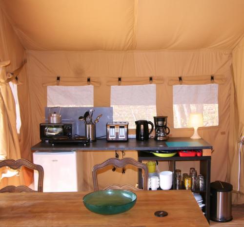a kitchen with a table and a counter in a tent at Safaritent Les Pourettes in Feusines