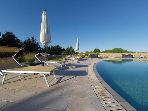 un gruppo di sedie e ombrelloni accanto alla piscina di Azienda Agrituristica Masseria La Verna a Patù