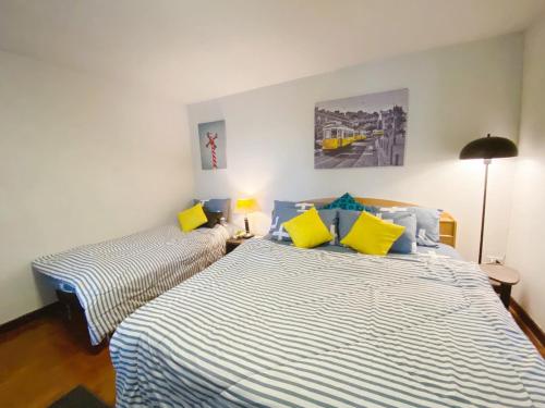 a bedroom with two beds with yellow and blue pillows at Cozy family room At 103 condominium 2 on nimman 12 in Chiang Mai
