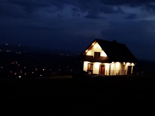 een huis 's nachts met lichten aan bij DOMEK W GÓRACH I NAD JEZIOREM CZORSZTYŃSKIM in Szlembark