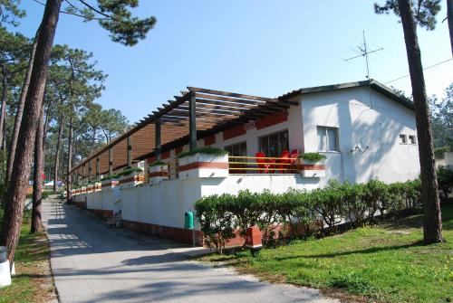 Casa blanca con balcón y árboles en Parque De Campismo Orbitur Sao Pedro De Moel, en São Pedro de Moel