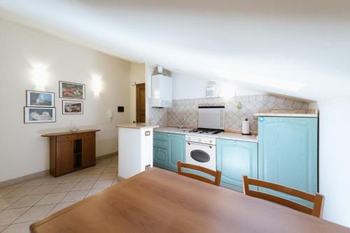 uma cozinha com armários azuis e uma mesa de madeira e uma mesa de mesa em Casa GINESTRA a Bagno Vignoni em Bagno Vignoni