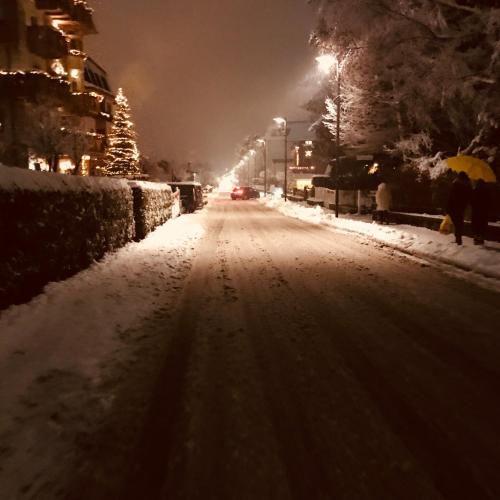 a snow covered street at night with a christmas tree at Sottovento Luxury Hospitality in Bormio