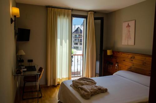 una camera d'albergo con un letto e una grande finestra di Albares a Vielha