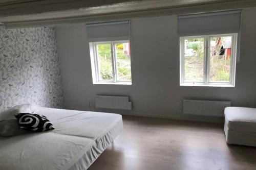 a white bedroom with a bed and two windows at Holiday home in Småland in Ryd