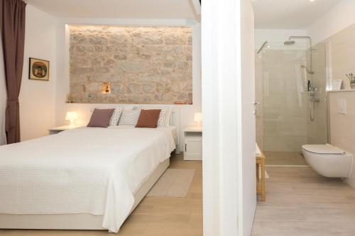 a bedroom with a white bed and a bathroom at Liberty Town Center Rooms in Dubrovnik