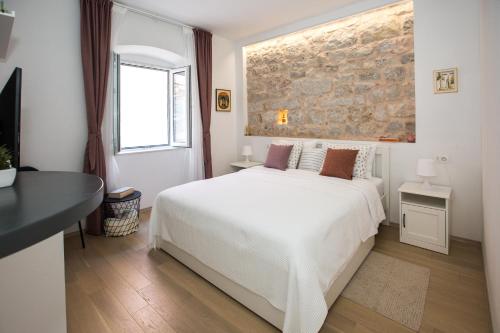 een slaapkamer met een wit bed en een bakstenen muur bij Liberty Town Center Rooms in Dubrovnik