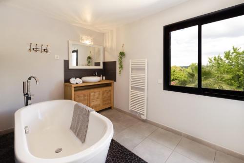 baño con bañera y ventana en Villa Holidays - Piscine chauffée et privée - clim - wifi - parking privée - Netflix, en Grabels
