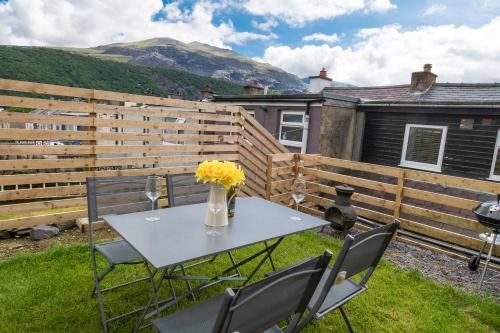 a patio with a table and chairs and a fence at Snowdon Street in Llanberis