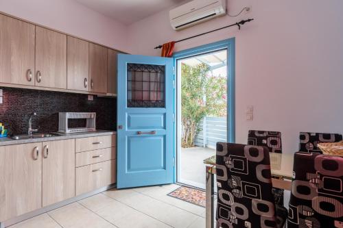 a kitchen with a blue door and a microwave at Adelphi Apartments in Perissa