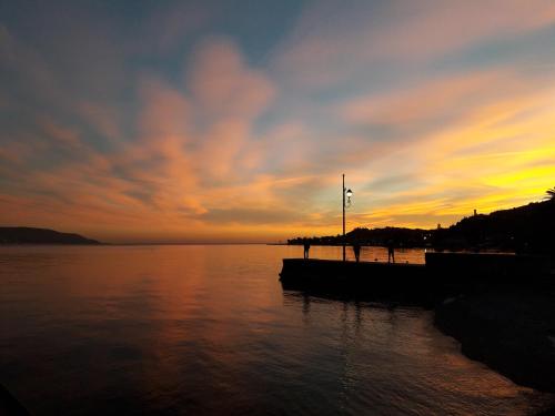 a sunset over a body of water with a boat at Cà del borgo Historic Village in Toscolano Maderno