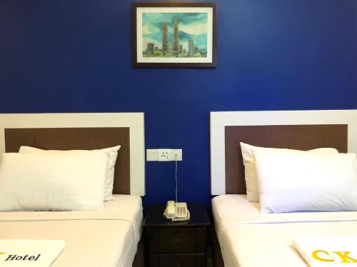 2 Betten in einem Zimmer mit blauer Wand in der Unterkunft CK Hotel in Malakka