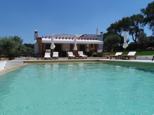 a swimming pool with chairs and a house at Quinta da Soneca in Alandroal