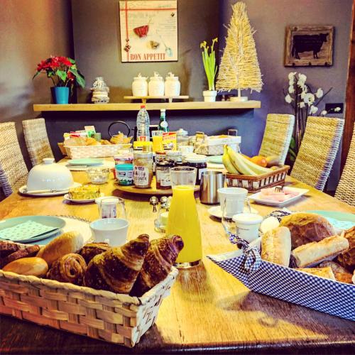 a wooden table with a table with bread and food at La Belle Étable in Dinant