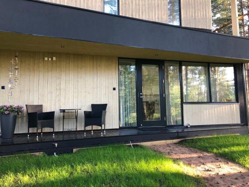 a house with chairs and a table on a porch at Sea View Studio Apartments by the Beach in Ihasalu