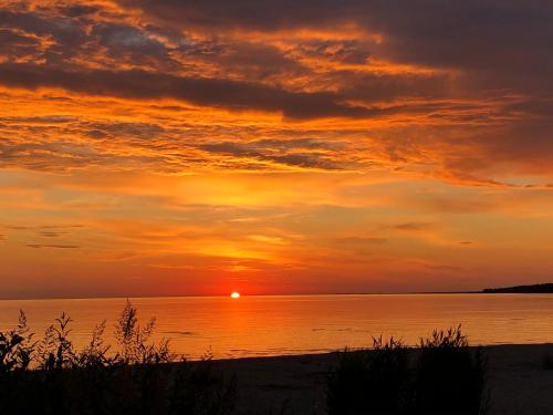 a sunset on the beach with the sun setting at Sea View Studio Apartments by the Beach in Ihasalu