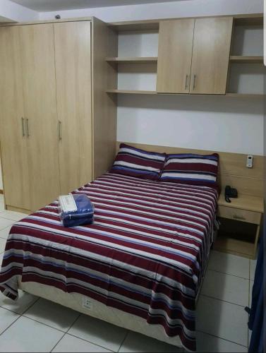 a bed with a striped blanket and a phone on it at FLAT BIARRITZ SETOR HOTELEIRO NORTE QUARTO 106 in Brasília