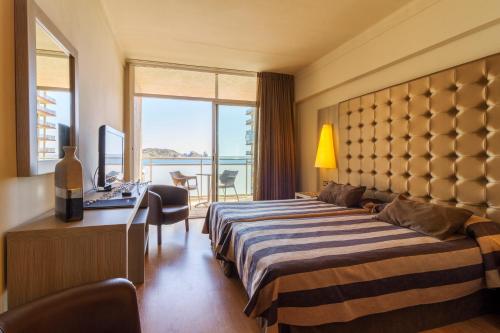 a hotel room with two beds and a desk and a window at Hotel Panorama in L'Estartit