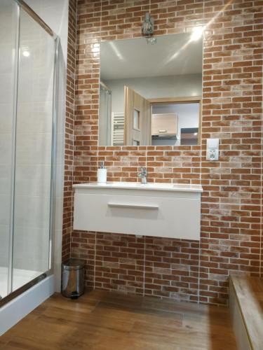 a bathroom with a white sink and a brick wall at Centrum Apartament Old Town in Świdnica