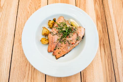 a plate of salmon and potatoes on a wooden table at Hundred House Hotel in Ironbridge