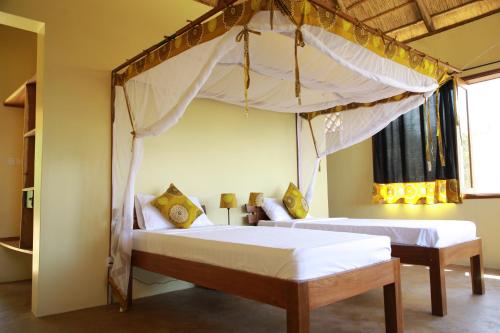 a bedroom with two beds and a canopy at Kikonko Lodge in Biseruka