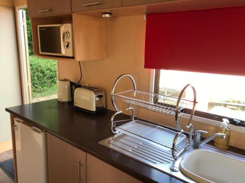 a kitchen with a dish drying rack and a sink at "Trinity" at Whitecliff Bay Isle of Wight- Yarborough View 4 in Bembridge