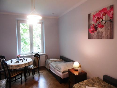 Cette chambre comprend un lit, une table et une fenêtre. dans l'établissement Apartament Orchidea, à Cracovie