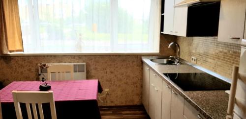 cocina con mesa rosa y fregadero en Vasaros apartamentas Nr3 en Palanga