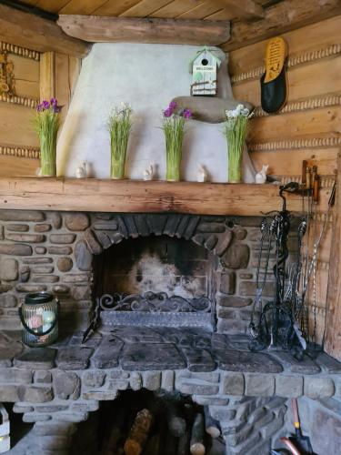a fireplace in a log cabin with flowers on the mantle at Durda in Poronin