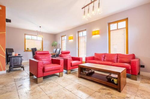 a living room with red couches and a table at PATEK Premium Apartments - Airport Lawica & MTP & Car races & International trade fairs in Skórzewo