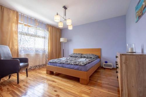 a bedroom with a bed and a chair and a window at PATEK Premium Apartments - Airport Lawica & MTP & Car races & International trade fairs in Skórzewo