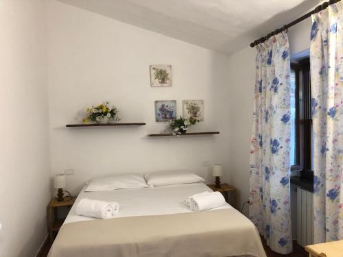 a bedroom with a bed with white sheets and a window at Agriturismo Santa Lorica in Sassetta