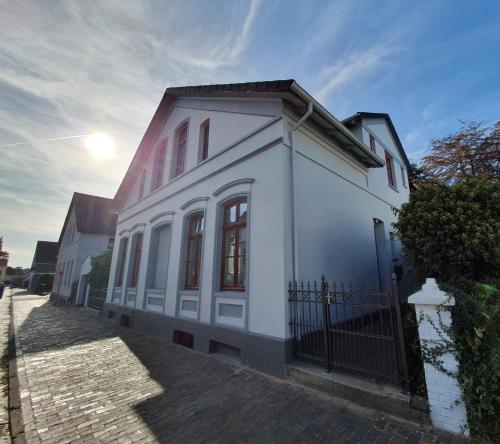 a white house with a fence in front of it at Stadtvilla Marie Varel Dangast 4 Personen mit Sauna in Varel