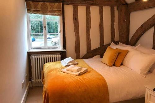 a bedroom with a bed with an orange blanket and a window at Stunning Cottage in Picturesque Village in Radlett