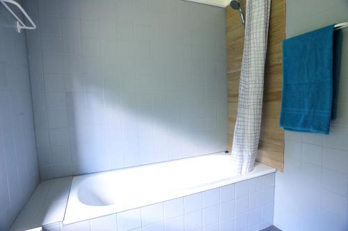 a bathroom with a white tub and a blue towel at La Babillarde in Auby-sur-Semois