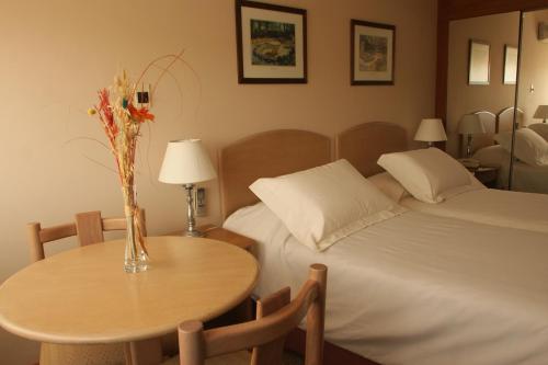 a bedroom with a bed and a table with a vase of flowers at Salto Grande Hotel in Punta del Este