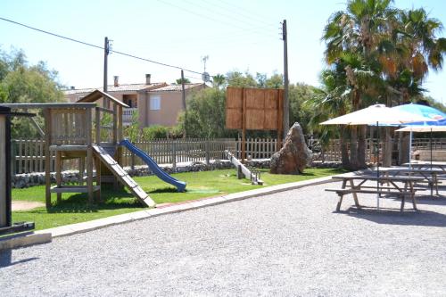 un parque infantil con tobogán, mesa y sombrilla en Ses Roques, en Alcudia