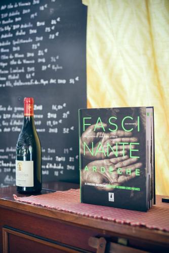 - une bouteille de vin et un livre sur une table dans l'établissement Chez Laurette, à Saint-Remèze