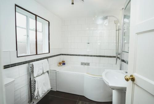 a white bathroom with a tub and a sink at Hundred House Hotel in Ironbridge