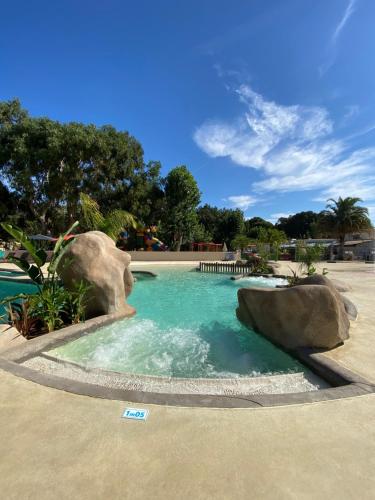 a swimming pool with a rock in the middle at Le Camping de la Plage in Aregno