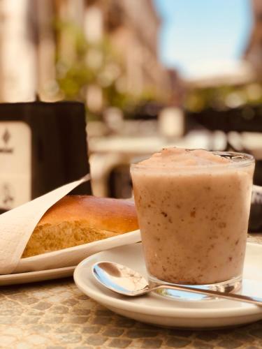 a drink and a piece of bread on a plate with a spoon at Il Galletto Viola, luxury room & suite in Palazzolo Acreide