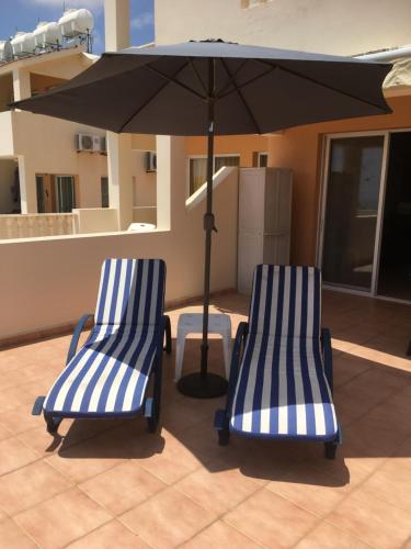 two blue and white chairs under an umbrella on a patio at Peyia Paradise Apartment B102 in Peyia
